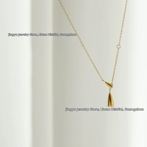 Detailed close-up of a polished gold water drop pendant on a minimalist 18K titanium chain