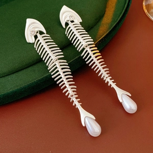 Macro shot of silver fishbone earrings with sparkling zircons and water drop pearls