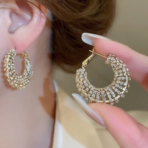 Detail of elegant gold-tone C-hoop earrings featuring multiple rows of sparkling rhinestones