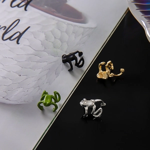 Vue détaillée de bagues d'oreille grenouille en noir mat, vert, doré et argenté
