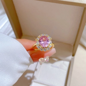 Detailed close-up of a luxury pink oval gemstone ring with a golden halo setting