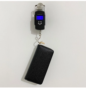 Detailed view of black litchi pattern wallet being weighed at 0.110kg for light travel