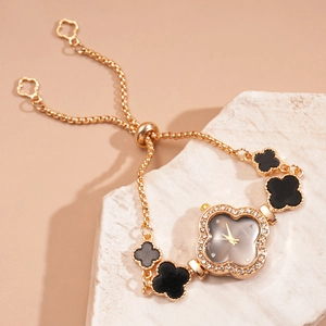 Detailed macro of gold clover bracelet watch with rhinestones on natural rock background