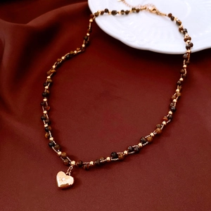 Detail of 18k gold plated tiger eye beaded necklace with a sparkling heart pendant