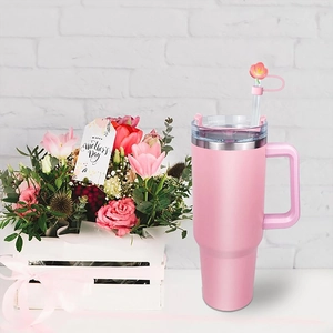 Pink travel tumbler with handle and floral straw topper set against a floral background