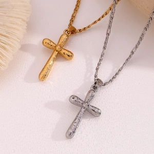 Detail of gold and silver cross necklaces with hammered texture on a light surface