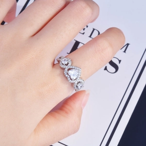 Three-heart silver engagement ring with pavé diamonds on a model's finger