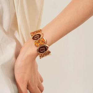 Détail d'un bracelet vintage doré avec étoiles en émail et motif géométrique au poignet