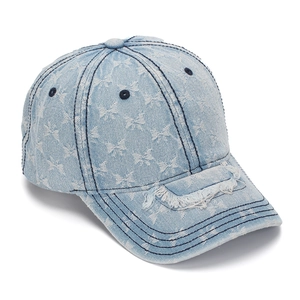 Close-up of distressed denim baseball cap with bow patterns and frayed brim details