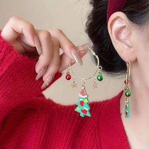 Weihnachtsbaum-Ohrringe mit Glocken an einem Model mit festlichem rotem Pullover