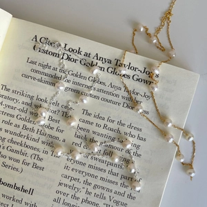 Baroque pearl necklace with gold and silver delicate chains on an open vintage book