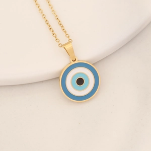 Golden stainless steel necklace with blue enamel Evil Eye pendant on white ceramic