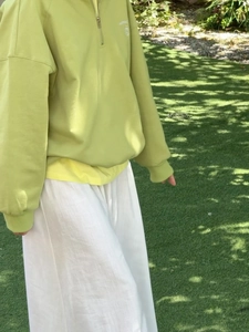 Foto exterior de una sudadera verde claro con media cremallera y bordado blanco INSPIRED