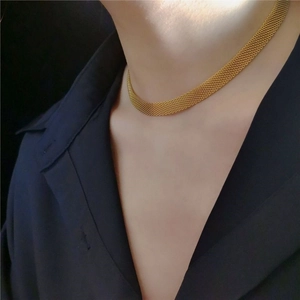 Dettaglio choker a maglia dorata che mostra la trama piatta intrecciata su un modello