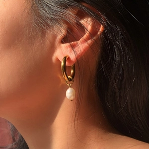 Close-up of gold titanium earring with irregular baroque freshwater pearl on model