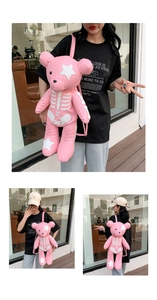 Pink teddy bear backpack with white skeleton pattern shown on female model in a cafe