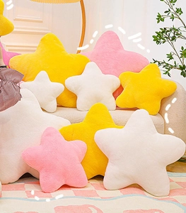 Plush star pillows in pink, yellow and white displayed on a cozy sofa and carpet
