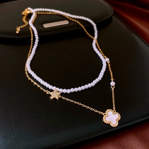 Close-up of double-layer pearl necklace with clover and star pendants on black leather