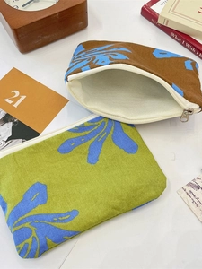 Floral canvas storage pouch with zipper for coins and cosmetics on a rustic wood background