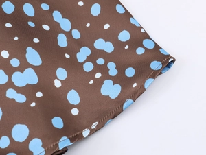 Detailed view of brown satin fabric with blue polka dots and professional hem stitching