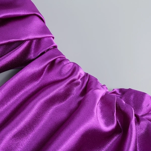 Détail d'une robe en satin violet luxueux montrant des plis élégants et un éclat soyeux