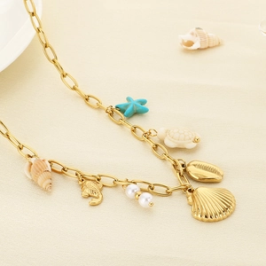 Macro shot of gold ocean charms including blue starfish, turtle, and pearls on a link chain