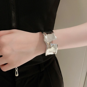 Detailed close-up of a silver irregular lava-style open bangle on a model's wrist
