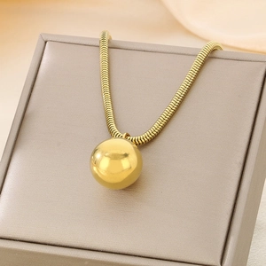 Detail of gold hollow sphere pendant and square snake chain on beige leather jewelry display