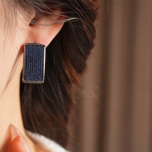 Close-up of model wearing dark blue rectangular cubic zirconia drop earrings in vintage style