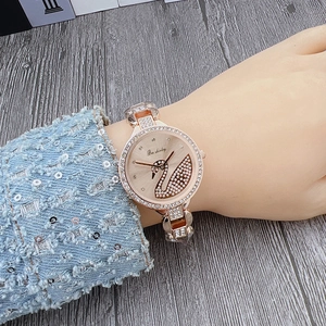 Close-up of rose gold square watch featuring a swan logo and crystal-embellished bezel
