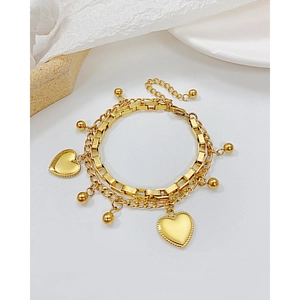 Detail of a gold double-layer stainless steel heart bracelet with beads and lobster clasp