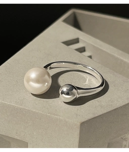 Macro shot of an open silver ring featuring a large pearl and small silver bead detail