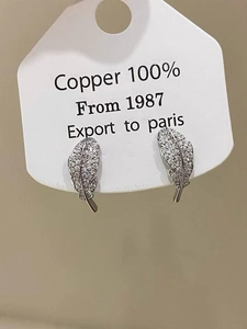 Macro view of feather-shaped silver earrings with micro-set zircon stones on display