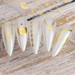 Détail macro de faux ongles amande blanc nacré avec motifs dorés d'ange et d'étoiles