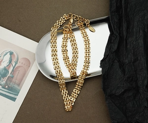 Detail of gold woven mesh link necklace and bracelet set displayed on a silver tray
