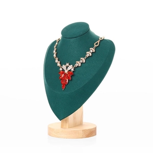 Macro view of a gold leafy necklace with red rhinestones on a green velvet bust stand
