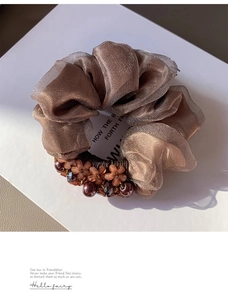 Close-up of coffee brown mesh scrunchie with floral beads and gemstone details