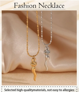 Detail of gold and silver necklaces with corno pendants on soft satin background