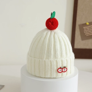 Detail of cream knit beanie featuring a red 3D apple pompom and fine apple embroidery