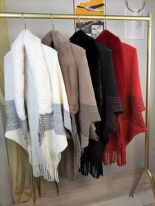 Detailed close-up of knit poncho shawls featuring faux fur collars and fringe tassels