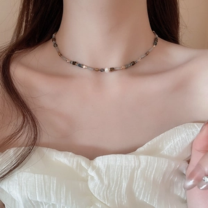 Close-up of minimalist beaded choker with agate and ceramic accents on model's neckline