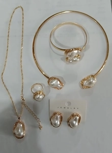 Flat lay of gold jewelry set with irregular baroque pearls on a light background