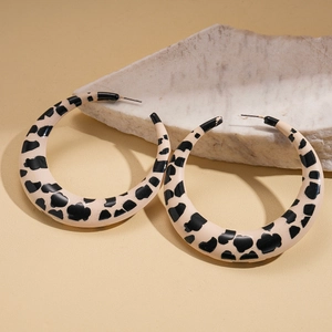 Detail shot of large crescent-shaped earrings with chic black and beige cow print patterns