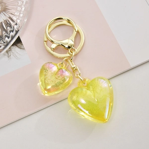 Macro detail of dual yellow resin heart pendants on a golden keychain accessory