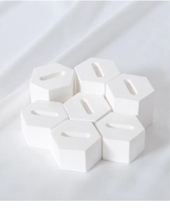 Set of seven white hexagonal ring holders with grooves on white textured fabric