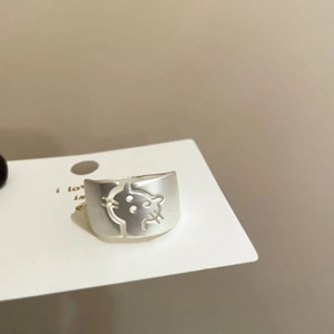 Detailed view of wide silver hollow cat ring with cute ears and whiskers on white card