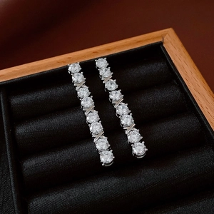Macro detail of silver tassel earrings with round crystals and X-shaped metal links