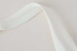 Close-up detail of white fabric shoulder strap with fine stitching and soft texture