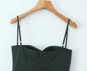 Detail of adjustable metal buckles on thin straps of a dark green backless dress