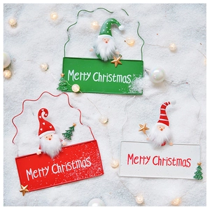 Close-up of Merry Christmas iron sign with plush Santa and tree on snowy background